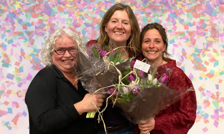 Drie vrouwen met stralende glimlach en bossen bloemen. Confetti op de achtergrond.