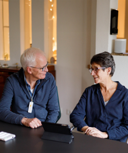 Oudere man en vrouw kijken elkaar aan, zitten aan tafel