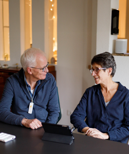 Oudere man en vrouw kijken elkaar aan, zitten aan tafel