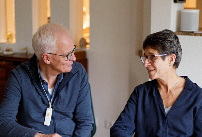 Oudere man en vrouw kijken elkaar aan, zitten aan tafel