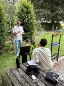 Man maakt gebaren, andere man zit achter telefoon of statief