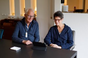 Oudere man en vrouw zitten aan tafel en kijken naar tablet op tafel