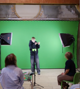 Man maakt gebaren in een foto studio, staat voor een greenscreen