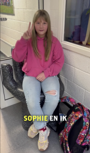 Jonge vrouw zit op stoel en maakt peace gebaar