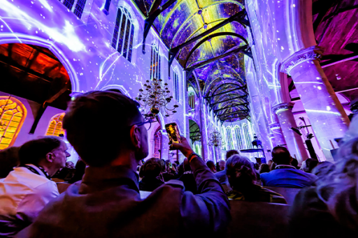 Verlichtte kerk met projecties in verschillende kleuren