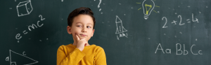 Klein kind kijkt bedenkelijk voor een schoolbord met tekeningen
