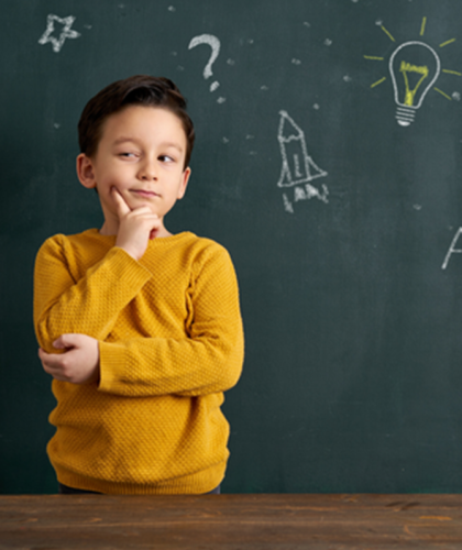 Klein kind kijkt bedenkelijk voor een schoolbord met tekeningen