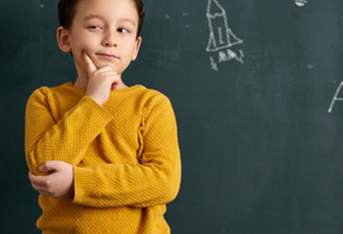 Klein kind kijkt bedenkelijk voor een schoolbord met tekeningen