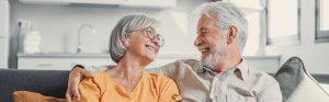 Oudere man en vrouw kijken elkaar blij aan op de bank
