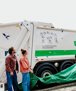 twee mensen naast vuilniswagen met gebaren