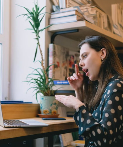vrouw kijkt naar laptop en maakt gebaren