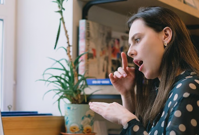 vrouw kijkt naar laptop en maakt gebaren